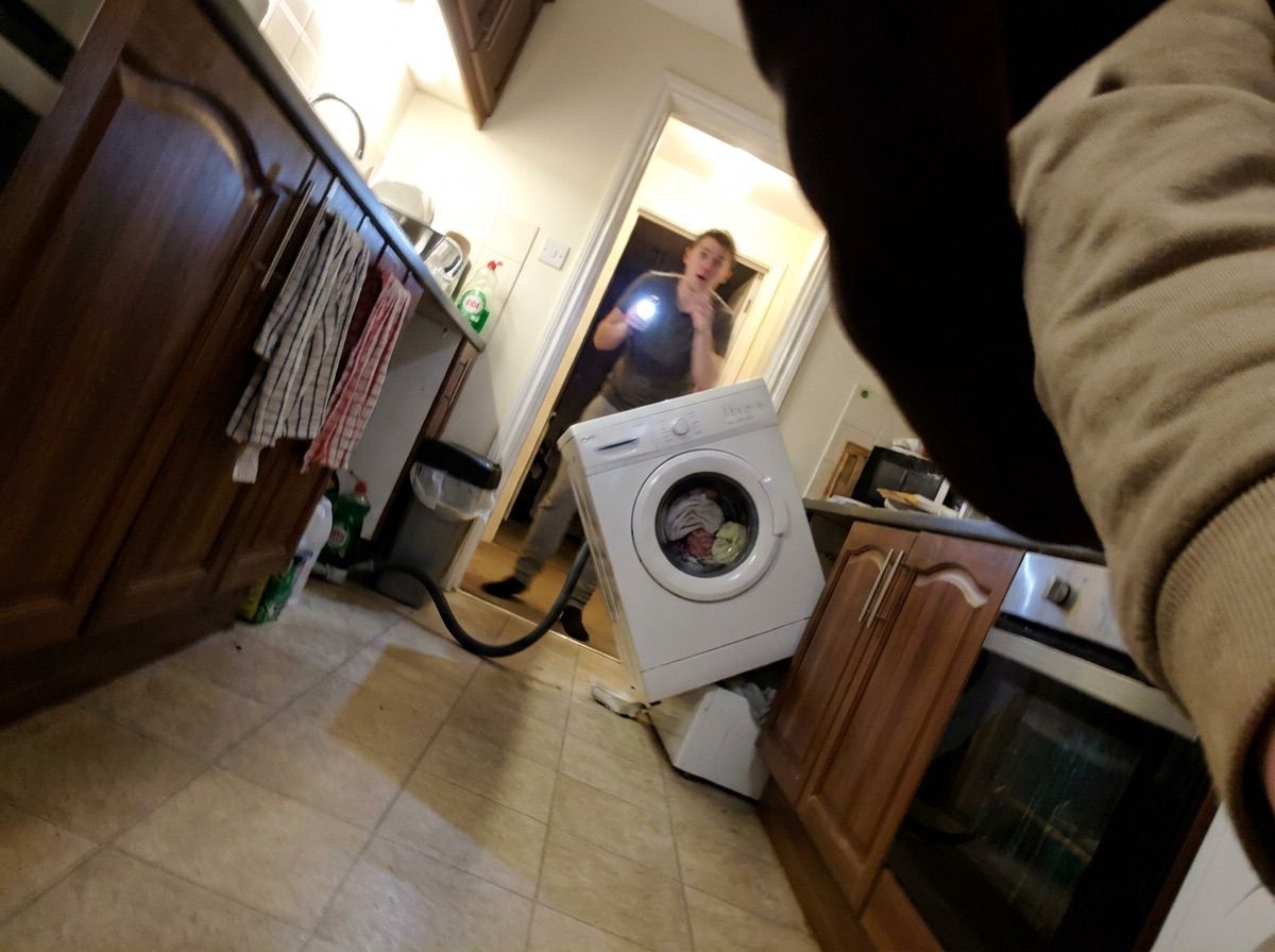 A person freezes in a doorway at night facing a washing machine that has moved into the room