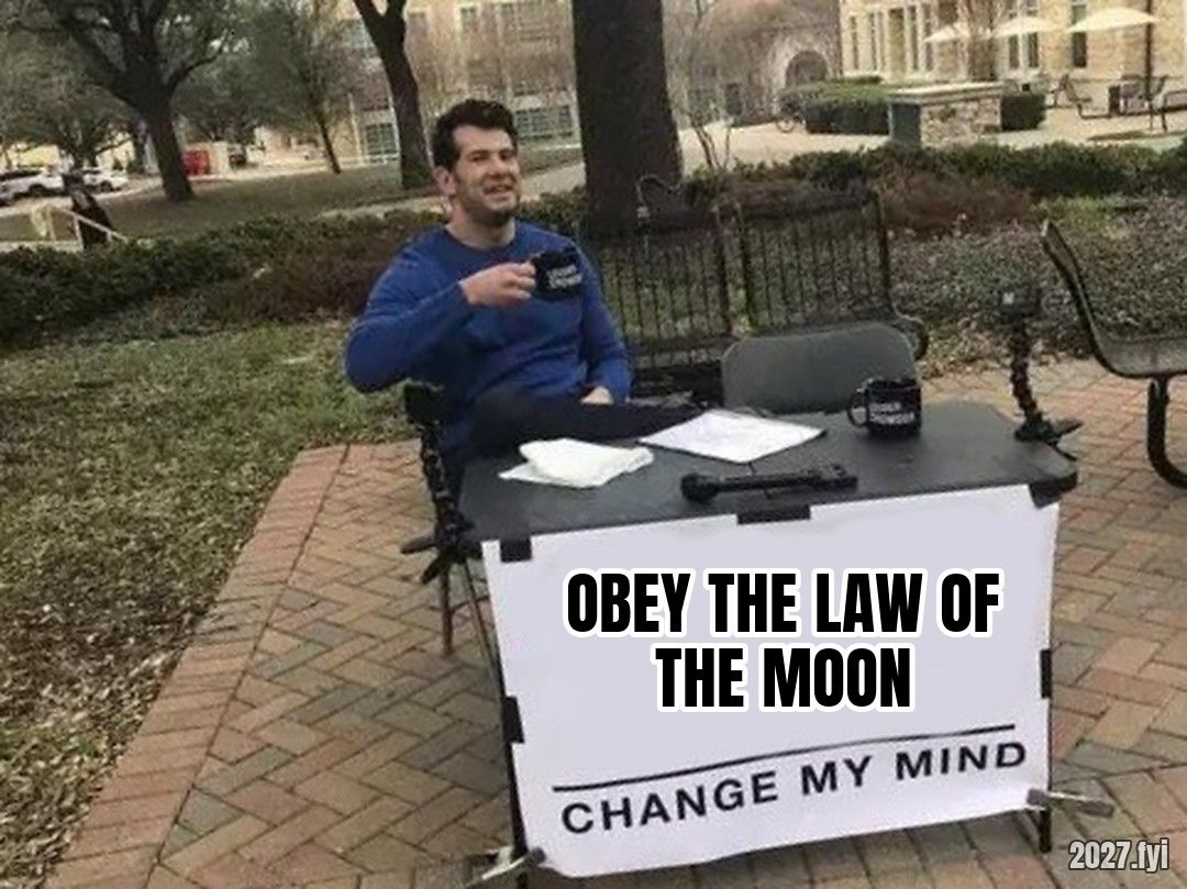 A man at a table with a sign: OBEY THE LAW OF THE MOON, CHANGE MY MIND